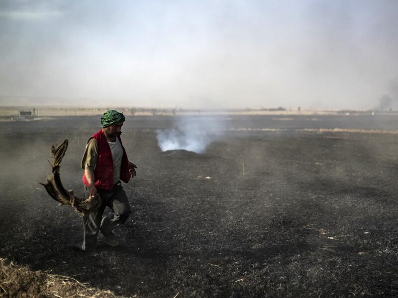 People battle a blaze next to an oil well in an agricultural field in the town of al-Qahtaniyah, in the Hasakeh province near the Syrian-Turkish border on June 10, 2019. Fires have erupted in various parts of Syria in recent weeks, with all sides blaming each other for starting them. Delil souleiman / AFP