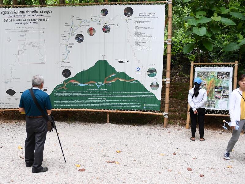 Tourists snap selfies by a bronze statue of the diver who died trying to save the 'Wild Boar' footballers from a flooded cave, while momentos from their rescue fly off the shelves -- scooped up by the 1.3 million people who have descended on a once serene mountainside in northern Thailand. Lillian SUWANRUMPHA / AFP