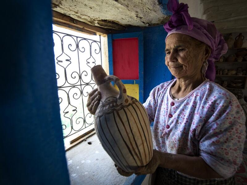 Moroccan potter Aicha Tabiz, also known as Mama Aicha, holds one of her works near the village of Ourtzagh in the foothills of the Rif mountains on June 12, 2019. Like everywhere in the Rif mountains, women potters from the Sless tribe, to which Aicha Tabiz's family belongs, are vanishing.  The tribe counted around 90 potters at the end of 1990s. Now, only a half-dozen remain.   FADEL SENNA / AFP