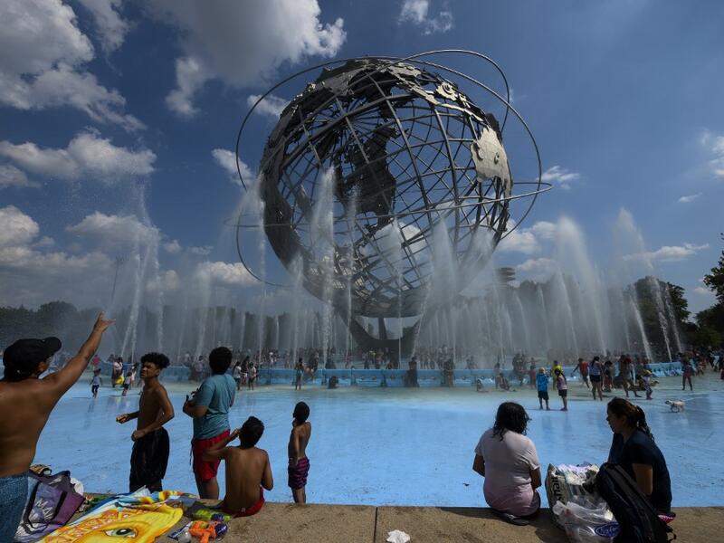 People enjoy refreshing water of a fountain in the Unisphere fountain at Flushing Meadow Corona Park in the borough of Queens on July 21, 2019 in New York City. Johannes EISELE / AFP