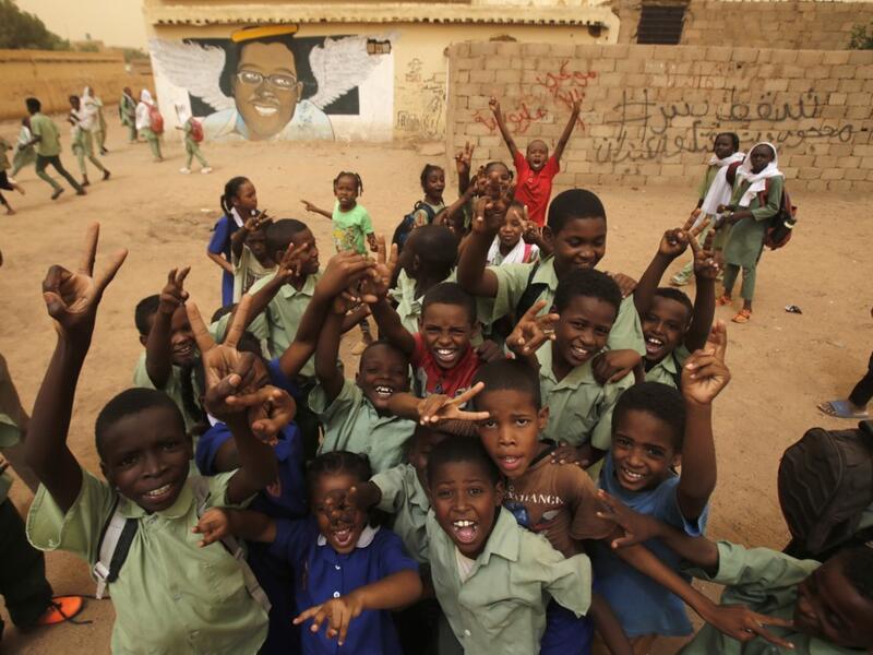 Pupils gesture in front of a mural painting of a protester killed during anti-government protests in the Sudanese capital Khartoum. ASHRAF SHAZLY / AFP