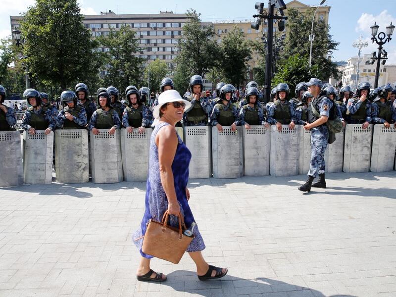 A woman walks past servicemen of the Russian National Guard during an unauthorised rally demanding independent and opposition candidates be allowed to run for office in local election in September, in downtown Moscow on July 27, 2019.  Maxim ZMEYEV / AFP