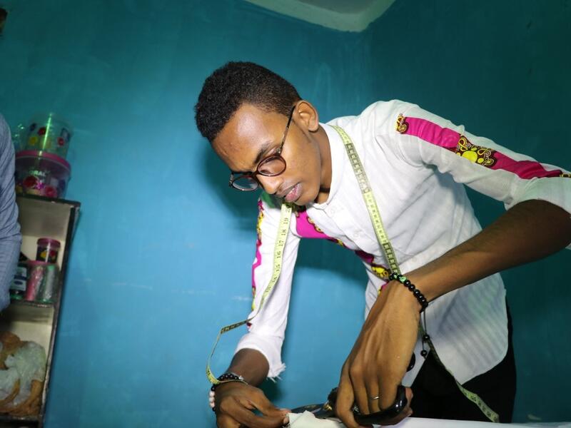 Abdishakur Abdirahman Adam, 19 years old, secondary school student and fashion designer for women and men, cuts fabrics, on November 4, 2018, in Mogadishu. Abdi HAJJI HUSSEIN / AFP
