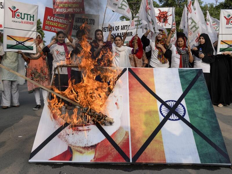 Activists of the 'Youth Forum for Kashmir' group shout slogans as they burn a picture of Indian Prime Minister Narendra Modi and the Indian flag during a protest in Lahore  ARIF ALI / AFP