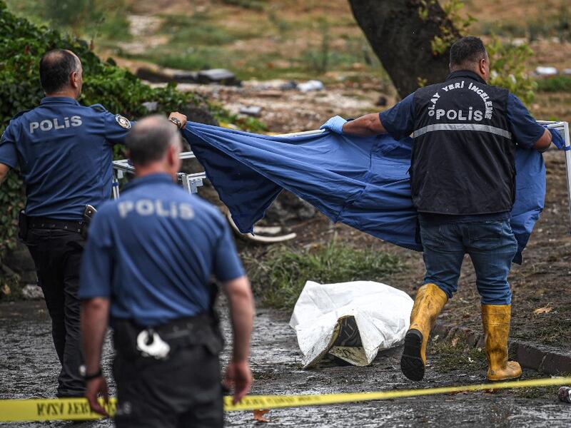 Turkish police officers cover a body on the ground in Eminonu district, Istanbul, after a heavy rainfall, on August 17, 2019. Turkey's mega city Istanbul was lashed by a heavy rainstorm on August 17, killing a homeless man and leaving parts of the historic Grand Bazaar flooded.  Ozan KOSE / AFP