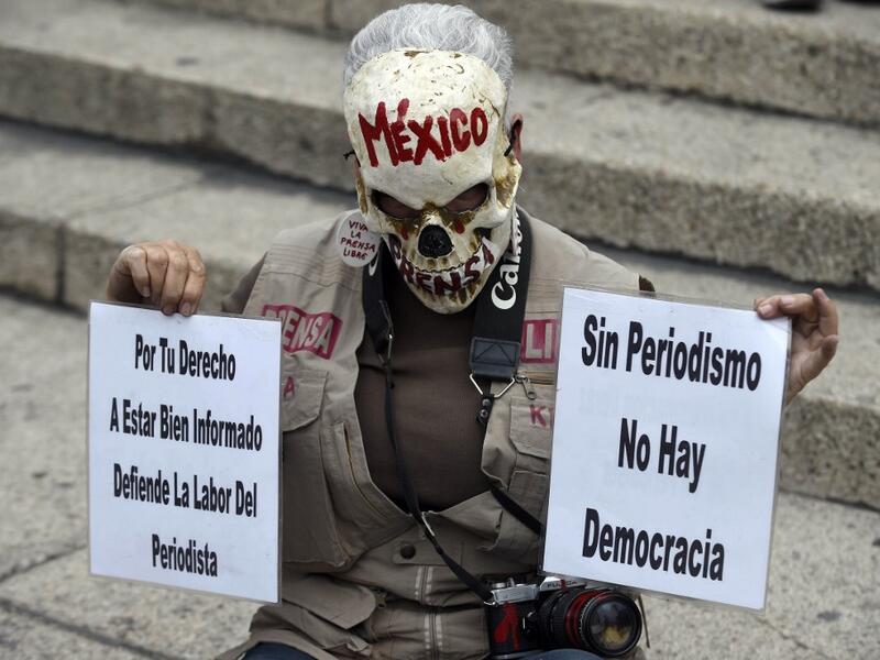 In this file photo taken on March 25, 2017 Mexican activist Julia Klug holds signs reading "For your right to be well informed, defend the journalist's work" and "Without journalism there is no democracy" during a protest against the murder of Mexican journalist Miroslava Breach, in Mexico City. ALFREDO ESTRELLA / AFP