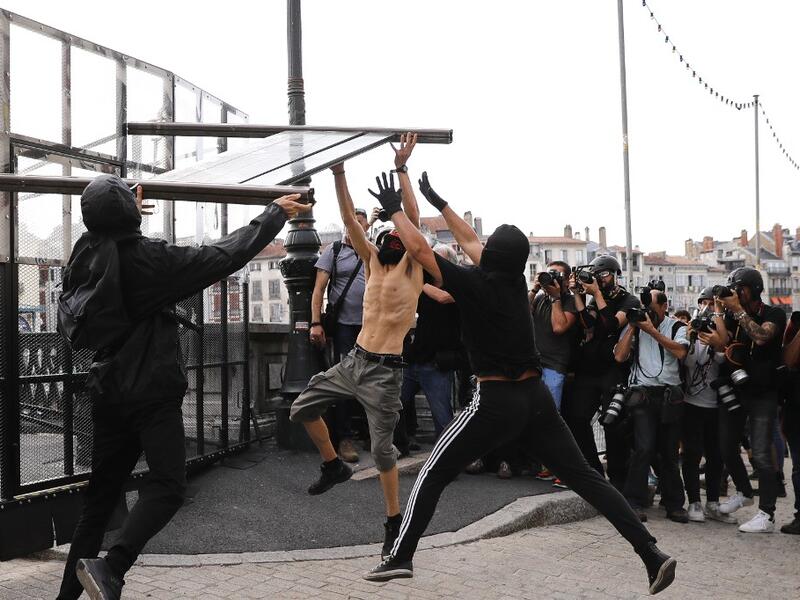 Photojournalist take pictures as three protesters tear down a barricade during demonstration in the city of Bayonne, south-west France on August 24, 2019, on the sidelines of the annual G7 Summit. Thomas SAMSON / AFP