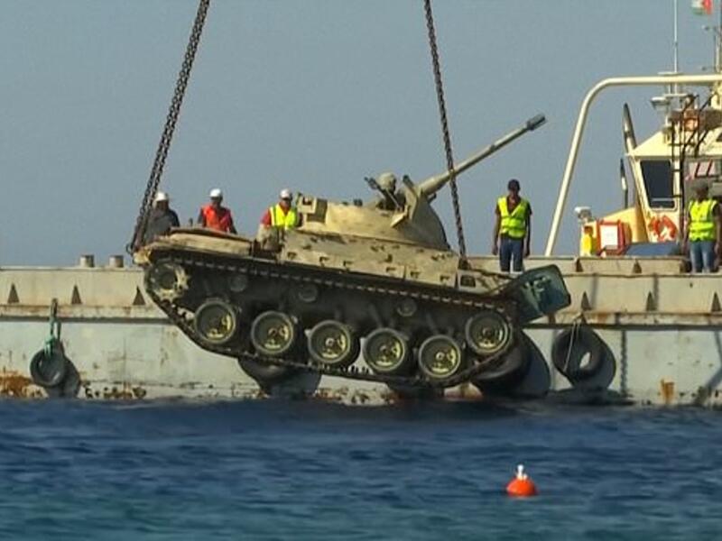 The crane lowers a Jordanian Armed Forces' armoured vehicle. (YouTube Screenshot)