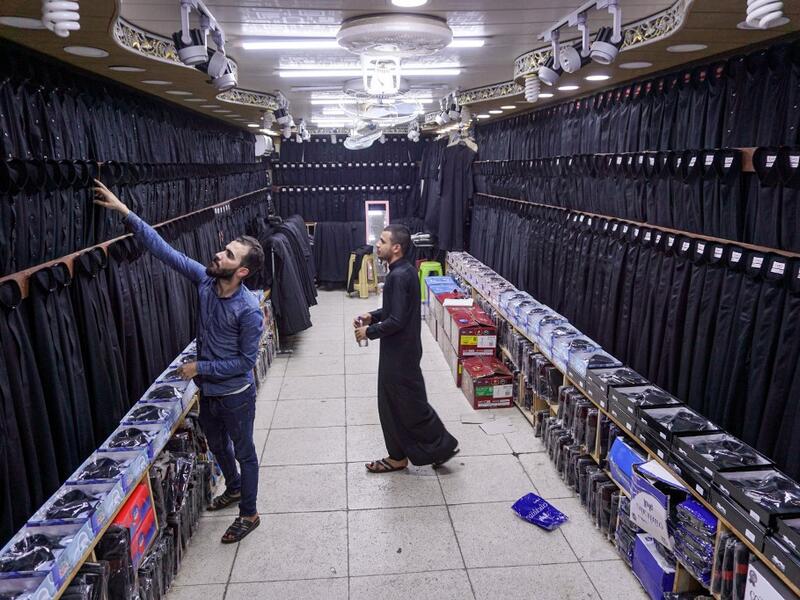 A man browses black garbs sold to Shiite Muslim pilgrims amidst preparations ahead of the Shiite religious mourning period of Ashura, in the central Iraqi holy shrine city of Najaf on August 31, 2019.  Haidar HAMDANI / AFP