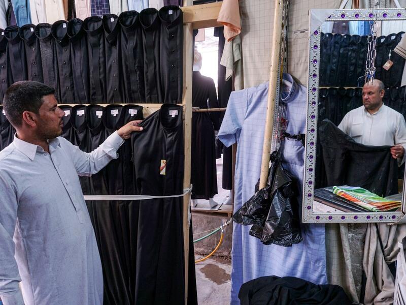 A man browses black garbs sold to Shiite Muslim pilgrims amidst preparations ahead of the Shiite religious mourning period of Ashura, in the central Iraqi holy shrine city of Najaf on August 31, 2019.  Haidar HAMDANI / AFP