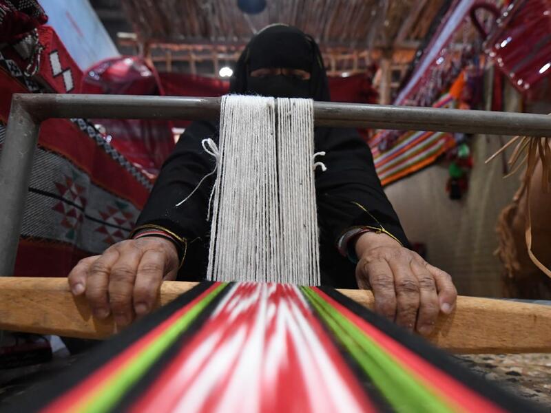 An Emirati woman works on a loom in a display of traditional crafts on the first day of the Abu Dhabi International Hunting and Equestrian exhibition (ADIHEX) in the UAE capital on August 31, 2019.  KARIM SAHIB / AFP