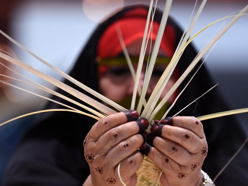 An Emirati woman knits together straw leaves in a display of traditional crafts on the first day of the Abu Dhabi International Hunting and Equestrian exhibition (ADIHEX) in the UAE capital on August 31, 2019.  KARIM SAHIB / AF