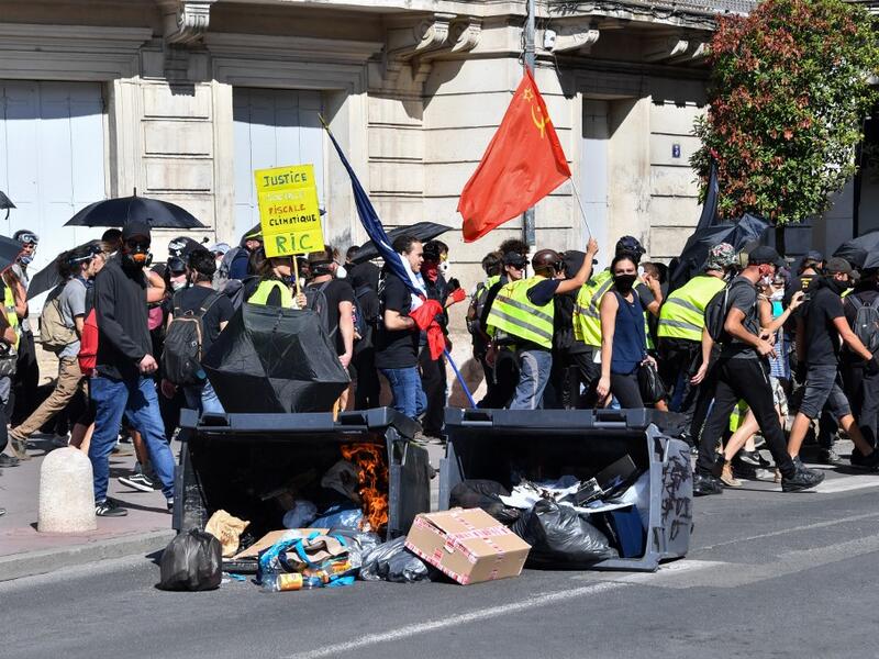 Protesters walk past burning trash bins during an anti-government demonstration called by the "Yellow Vests" (Gilets Jaunes) movement on September 7, 2019 in Montpellier, southern France. Pascal GUYOT / AFP