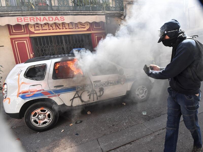 A protester dressed in black takes a picture of a burning French Municipal Police car on the sidelines of an anti-government demonstration called by the "Yellow Vests" (Gilets Jaunes) movement in Montpellier, southern France, on September 7, 2019. Pascal GUYOT / AFP