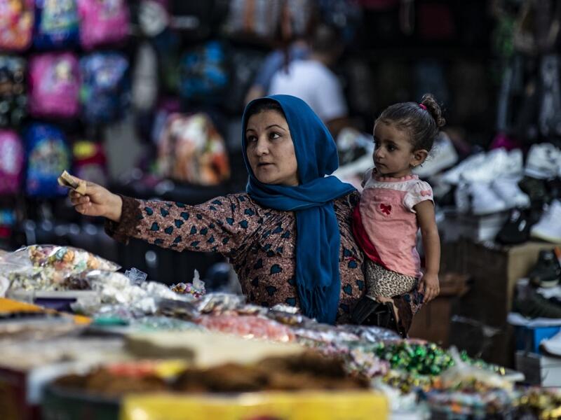 A woman pays a merchant at a market in the Kurdish-majority city of Qamishli in northeast Syria.  Delil SOULEIMAN / AFP