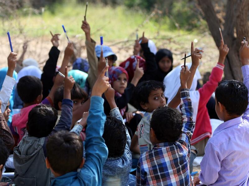 School children attend an open-air class under a tree near their unfinished school  Ahmad AL-BASHA / AFP