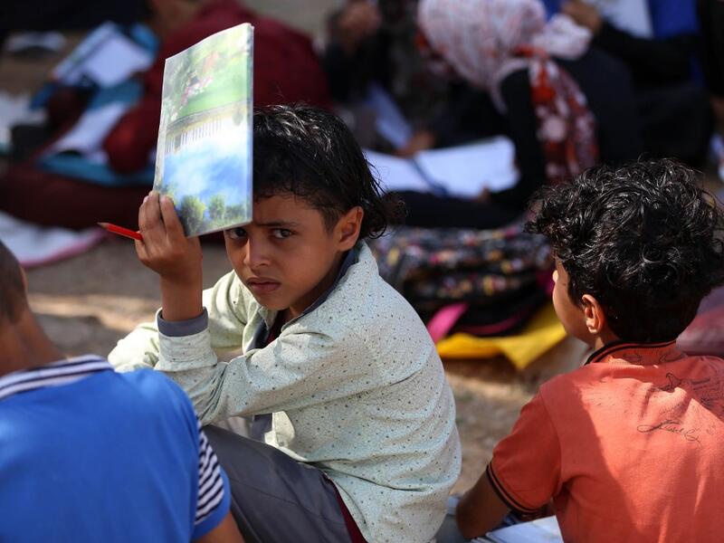 School children attend an open-air class under a tree near their unfinished school  Ahmad AL-BASHA / AFP