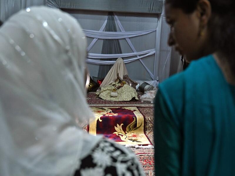In this photo taken on September 15, 2019, guests look at a bride (C) with her face and body covered with a shawl sits in her new husband's home following their marriage in Kashmir's Baramulla district, north of Srinagar. TAUSEEF MUSTAFA / AFP