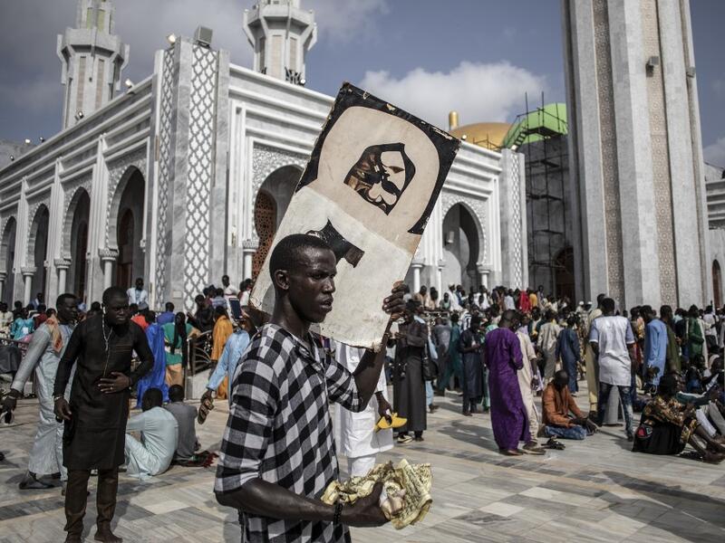 A worshipper holds a poster of Sante Serigne Touba Mbacke while waiting outside the Great Mosque of the Mourides on September 27, 2019 in Dakar, ahead of its inauguration. Senegal's influential Mouride Brotherhood will inaugurate a 30,000-capacity mosque in the capital Dakar, said to be the largest in West Africa. JOHN WESSELS / AFP