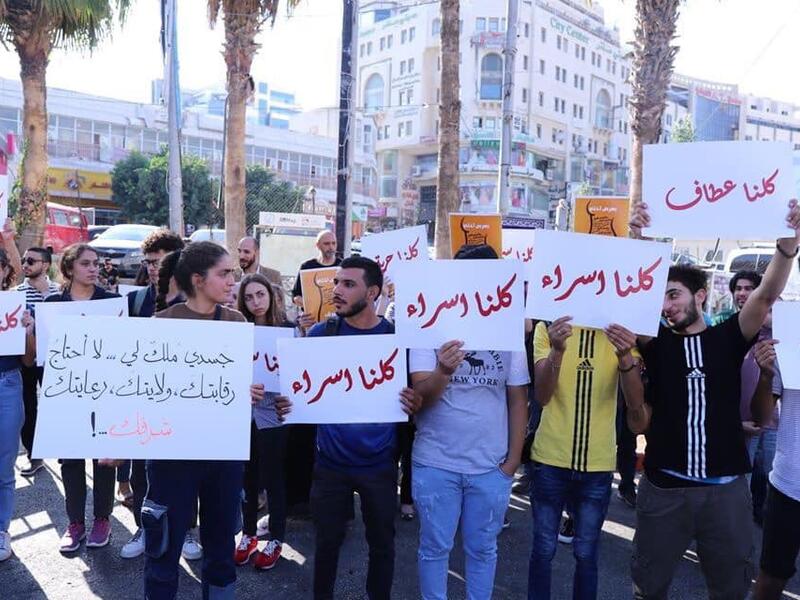 Arabic slogans on placards call for an end to violence against women and introducing a law for family protection against domestic violence."  (Twitter)