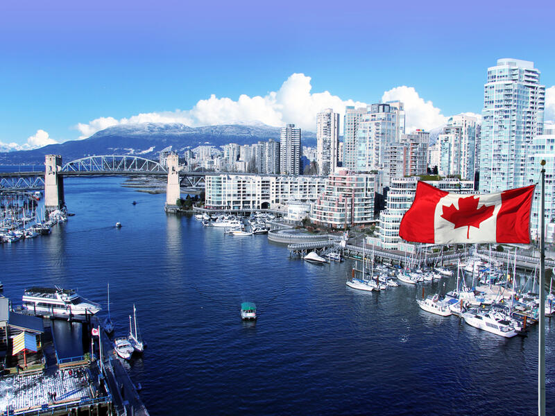 Canadian flag in front of view of False Creek and the Burrard street bridge in Vancouver, Canada (Shutterstock) Canadian flag in front of view of False Creek and the Burrard street bridge in Vancouver, Canada (Shutterstock)