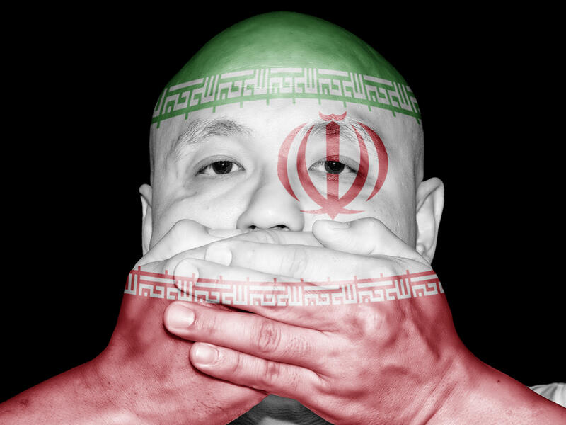A man covering his mouth with his hand with imprint of Iran flag (Shutterstock) A man covering his mouth with his hand with imprint of Iran flag (Shutterstock)