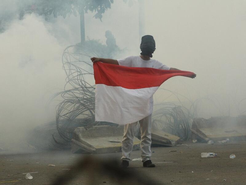 A protester carries the national flag through teargas smoke during a demonstration in Jakarta on September 30, 2019. (AFP/ File Photo)