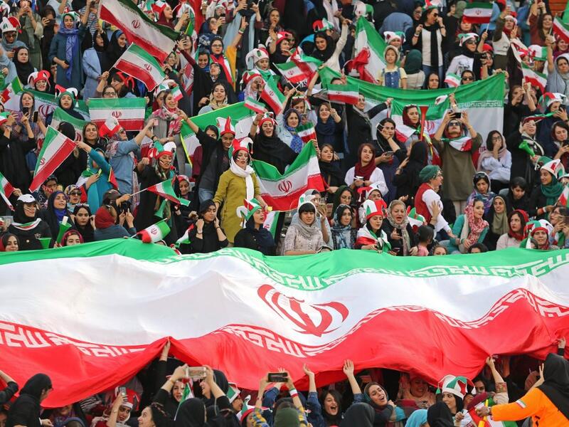 Iranian women cheer and wave their country's national flags as they attend the World Cup Qatar 2022 Group C qualification football match between Iran and Cambodia at the Azadi stadium in the capital Tehran on October 10, 2019. ATTA KENARE / AFP