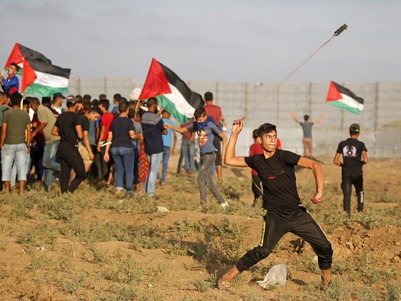 A Palestinian protester uses a slingshot to hurl stones during clashes with Israeli forces following a demonstration by the border fence between the Gaza Strip and Israel, east of Gaza City, on October 11, 2019. (SAID KHATIB / AFP)