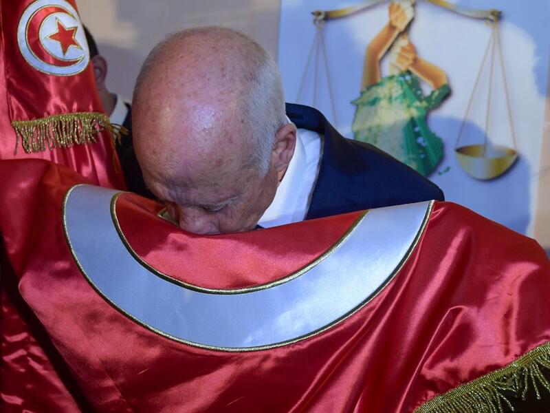 Conservative academic Kais Saied kisses the Tunisian flag as he celebrates his victory in the Tunisian presidential election in the capital Tunis on October 13, 2019. Saied won a landslide victory in Tunisia's presidential runoff, sweeping aside his rival, media magnate Nabil Karoui, state television Wataniya said. It said he scooped almost 77 percent of the vote, compared to 23 percent for Karoui. Fethi Belaid / AFP