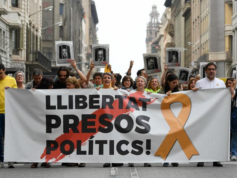 People protest holding a banner reading "Free political prisoners" in Barcelona on October 14, 2019, after Spain's Supreme Court sentenced nine Catalan leaders to prison terms ranging from nine to 13 years for sedition and misuse of public funds for their role in a failed 2017 independence bid. (LLUIS GENE / AFP) People protest holding a banner reading "Free political prisoners" in Barcelona on October 14, 2019, after Spain's Supreme Court sentenced nine Catalan leaders to prison terms ranging from nine to 13 years for sedition and misuse of public funds for their role in a failed 2017 independence bid. (LLUIS GENE / AFP)