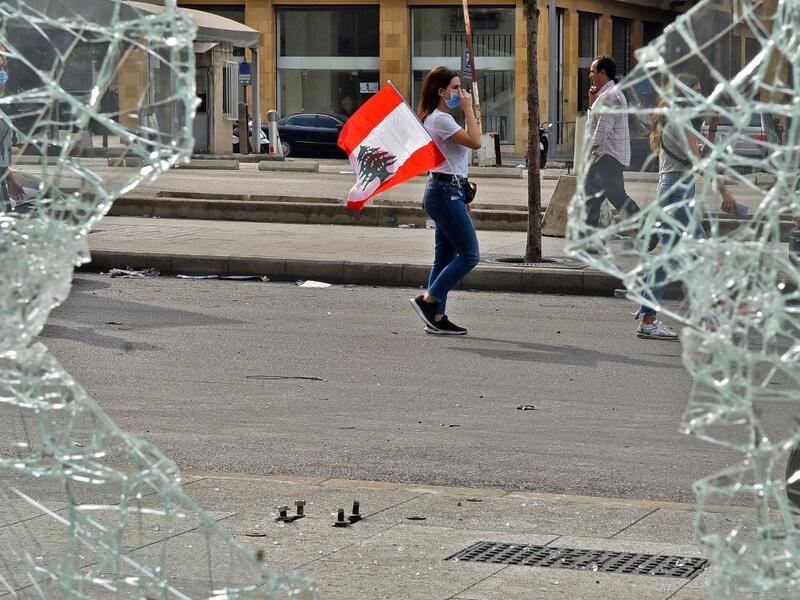 A masked woman walks with a Lebanese national flag tucked into her pocket past a broken window along a street in the centre of the capital Beirut on October 18, 2019 amidst ongoing protests against dire economic conditions. Public anger has simmered since parliament passed an austerity budget in July to help trim a ballooning deficit and flared on October 17 over new plans to tax calls on messaging applications such as WhatsApp, forcing the government to axe the unpopular proposal. AFP