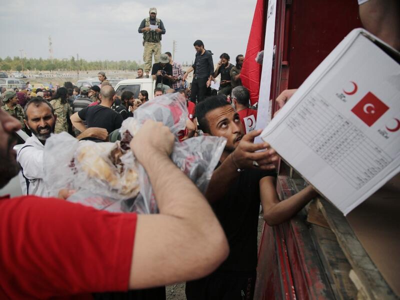 Displaced Syrians receive aid boxes provided by the Turkish Red Crescent on October 19, 2019, in the Syrian border town of of Tal Abyad which was seized by Turkey-backed forces last week. Bakr ALKASEM / AFP