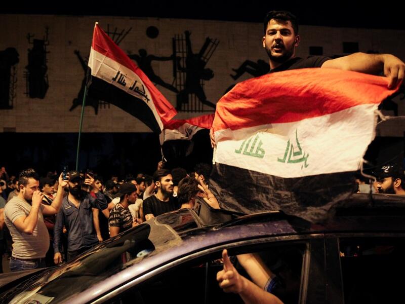 Iraqi protestors wave Iraq's national flags frome a car;s sun-roof as they take part in anti-government demonstrations in Baghdad's Tahrir Square on October 24, 2019. Anti-government rallies renewed across Iraq late on October 24, 2019, the second phase of protests denouncing corruption and unemployment before evolving into calls for an overhaul of the political system that turned deadly earlier this month and which could balloon after the endorsement of populist cleric Moqtada al-Sadr. AFP