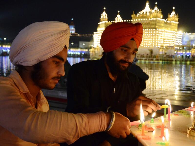 Indian Sikh devotees light candles as they pay their respects on the eve of "Bandi Chhor Divas" or "Diwali" at the illuminated Golden Temple, in Amritsar on October 26, 2019. Sikhs celebrate 'Bandi Chhor Divas', also on the same day as the Hindu festival of Diwali, to mark the historic return of the sixth Guru, Guru Hargobind NARINDER NANU / AFP