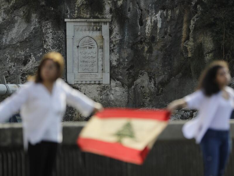 A picture taken on October 27, 2019, shows Lebanese protesters holding hands in the Nahr al-Kalb area, north of Beirut, to form a human chain along the coast from north to south as a symbol of unity, as part of ongoing anti-government demonstrations. The commemorative plaque carved in rock marks the full withdrawal of foreign troups in 1946, a couple of years after Lebanon's independence from the French mandate. JOSEPH EID / AFP