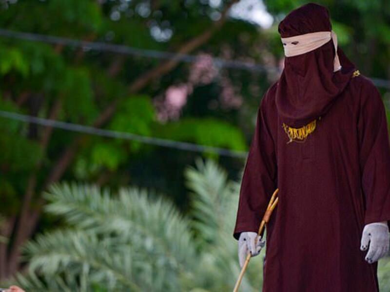 A member of the Sharia police can be seen standing ahead of the public caning in Banda Aceh on October 21, 2019 (AFP/dailymail.co.uk)