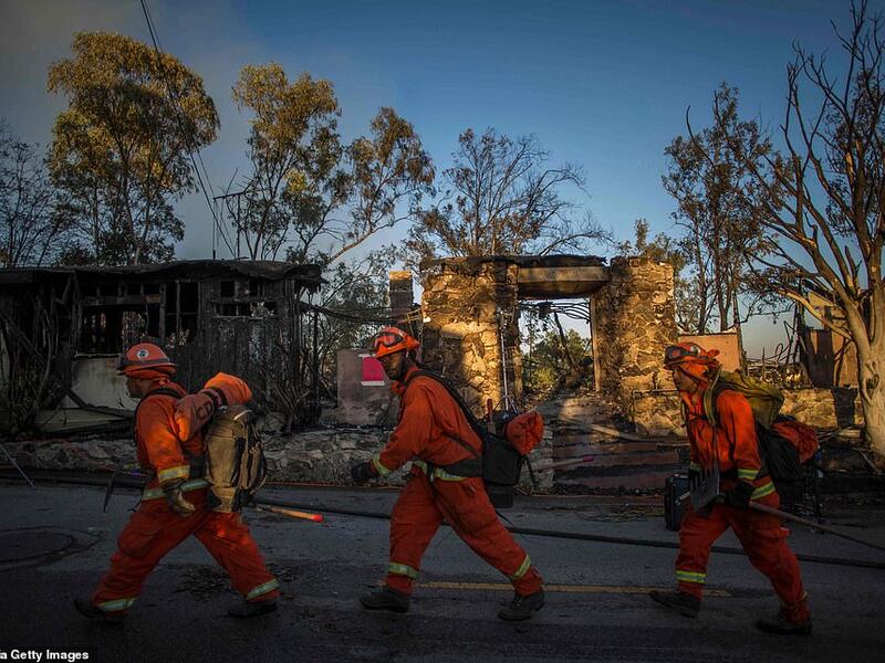 Into the inferno: Inmate firefighters walk past a burned home as they prepare to battle the wind-driven blaze in Brentwood, California which has destroyed several homes and forced schools to shut. (AFP)
