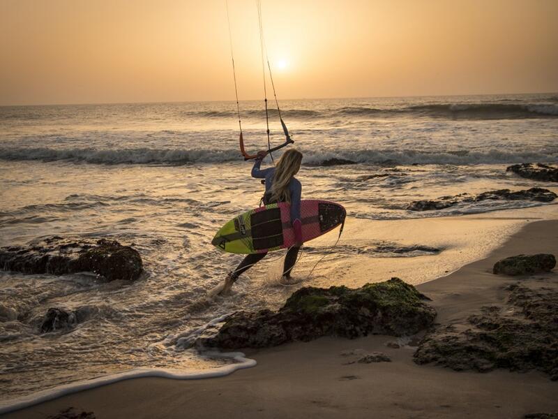 A picture taken on October 10, 2019, shows a kitesurfer holding her kite as she walks away at Dakhla beach in Morocco-administered Western Sahara. In the heart of disputed Western Sahara, a former garrison town has become an unlikely tourist magnet after kitesurfers discovered the windswept desert coast on the Atlantic is perfect for their sport. FADEL SENNA / AFP
