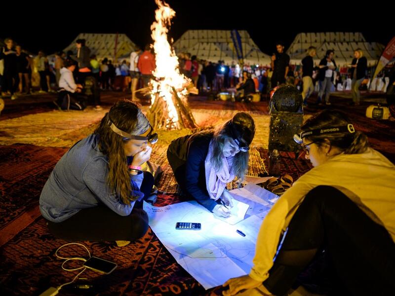 Women read and look at their map at the resting camp as they take part in the desert trek "Rose Trip Maroc", on October 31, 2019 in the erg Chebbi near Merzouga. The Rose Trip Maroc is a female-oriented trek where teams of three must travel through the southern Moroccan Sahara desert with a compass, a map and a topographical reporter. JEAN-PHILIPPE KSIAZEK / AFP