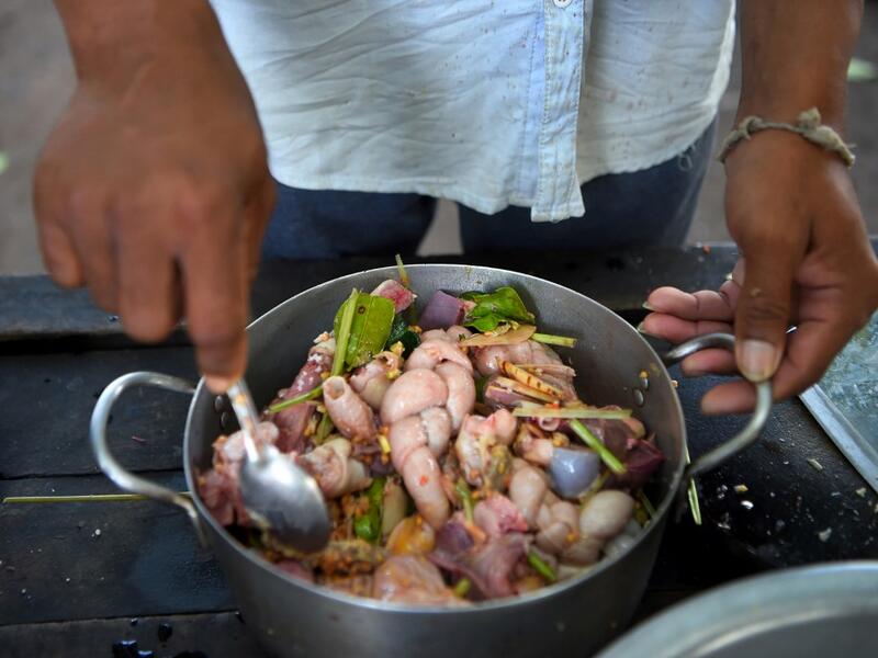 This photo taken on October 25, 2019 shows a man preparing to cook dog meat at a slaughterhouse in Siem Reap province. Cambodian dog meat traders drown, strangle and stab thousands of canines a day in a shadowy but sprawling business that traumatises workers and exposes them to deadly health risks like rabies. TANG CHHIN Sothy / AFP