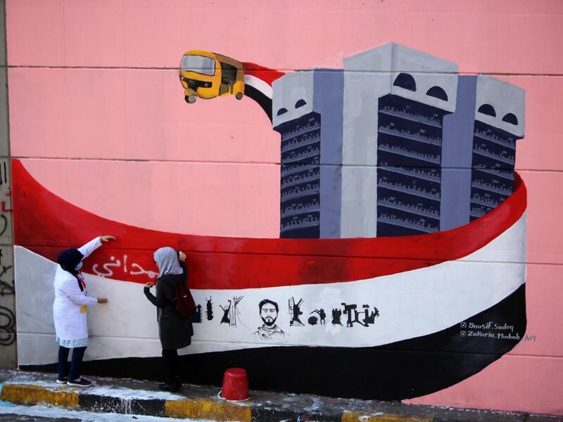 Iraqi demonstrators rest in front of a mural painting in Tahrir square during ongoing anti-government demonstrations in the capital Baghdad on November 2, 2019. The demonstrations have evolved since October 1 from rage over corruption and unemployment to demands for a total government overhaul, shunning both politicians and religious figures along the way. SABAH ARAR / AFP