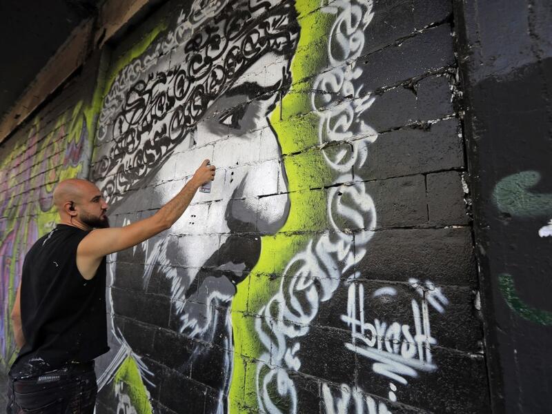 Graffiti artist Mohammad Abrashh draws a graffiti on the wall of a building at the al-Nour Square in the northern port city of Tripoli on November 7, 2019. An unprecedented protest movement has gripped Lebanon since October 17, demanding an overhaul of a political class that has remained largely unchanged since the end of the country's 1975-1990 civil war. In the northern city of Tripoli, where mobilisation has been relentless since the protests erupted on October 17, demonstrators took down politicians' po
