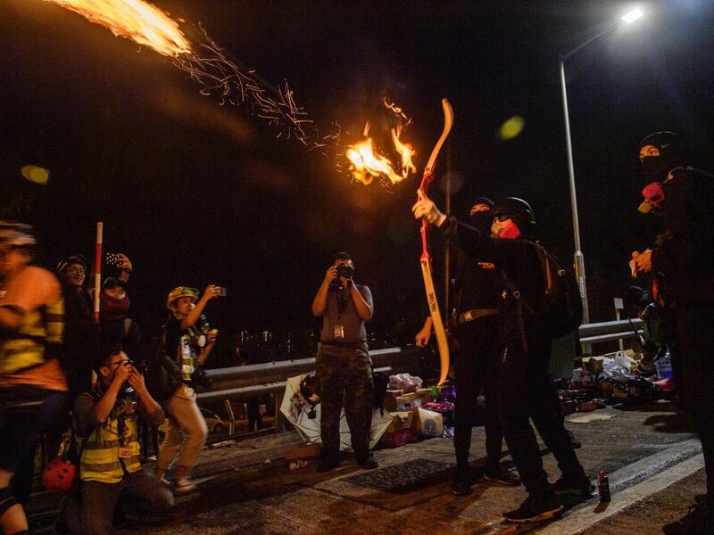 A protester releases a fire arrow with his bow to light a barricade at the Chinese University of Hong Kong (CUHK), in Hong Kong early on November 13, 2019. Hong Kong pro-democracy protesters fought intense battles with riot police on a university campus and paralysed the city's upmarket business district Tuesday, extending one of the most violent stretches of unrest seen in more than five months of political chaos. Anthony WALLACE / AFP