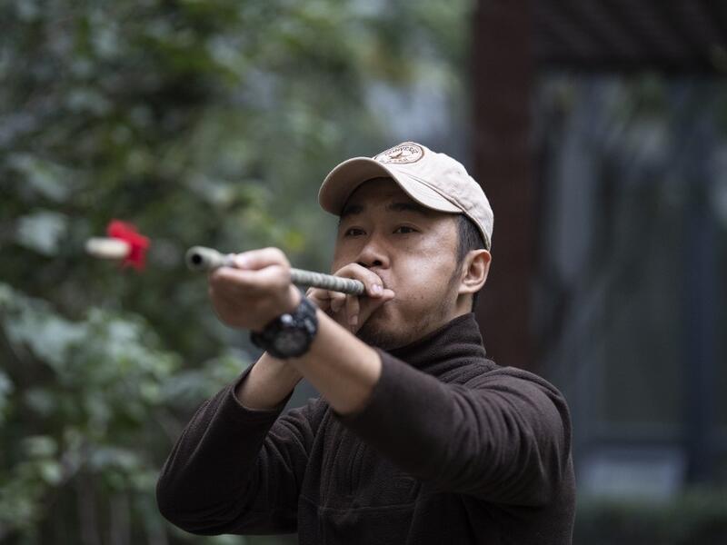 This photo taken on October 23, 2019 shows pet detective Sun Jinrong testing his blowdart as he prepares to search for a missing cat in a residential compound in Beijing. Private sleuth Sun Jinrong brings heat detectors, tiny surveillance cameras, and a blowdart loaded with a tranquiliser to his search for one desperate client's missing loved one: A cat named Duoduo.  NOEL CELIS / AFP