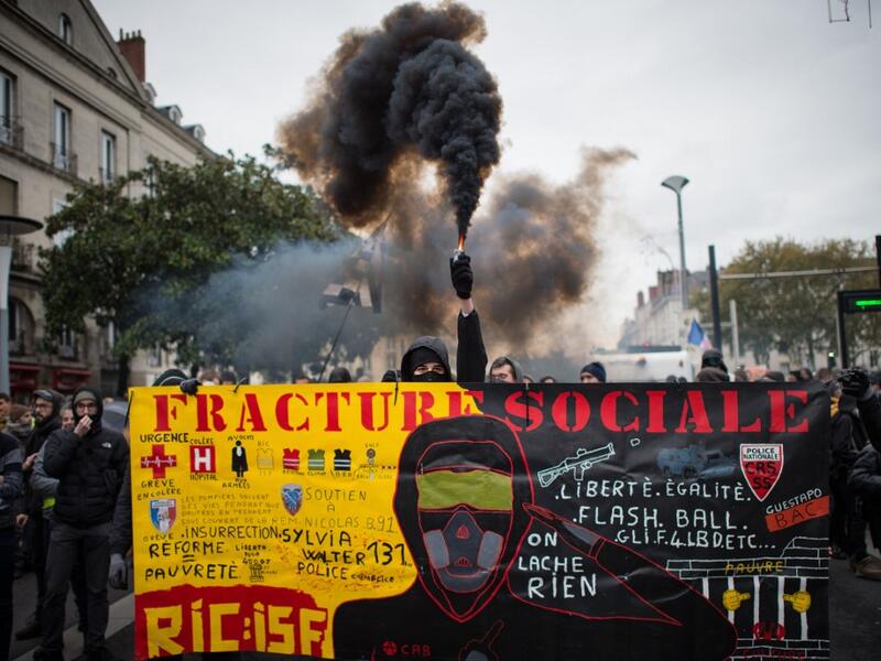 A demonstrator holds a smoke generator during a demonstration marking the first anniversary of the "yellow vest" (gilets jaunes) movement on November 16, 2019, in Nantes, western France. (LOIC VENANCE / AFP)