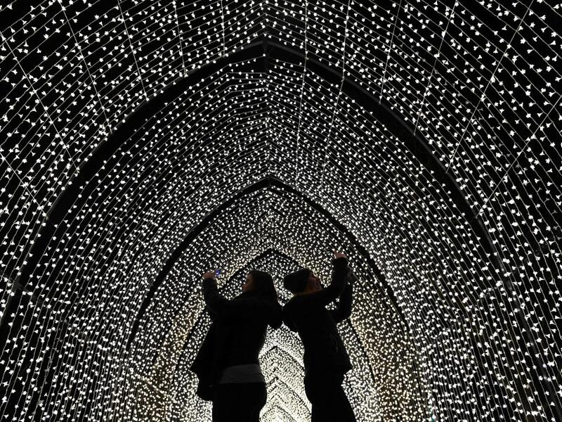 Visitors walk through the 'By Frost' tunnel of lights during a photocall at Kew Gardens in south west London, on November 19, 2019, during an event to promote the launch of the "Christmas at Kew" event. The Christmas at Kew trail is illuminated with numerous light-art installations especially commissioned. Daniel LEAL-OLIVAS / AFP