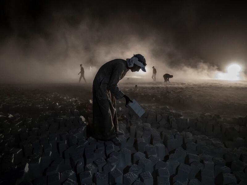 A labourer carries a stone block while working late at the "White Mountain" limestone extraction quarry site near Egypt's southern city of Minya, some 265 kilometres south of the capital, on November 13, 2019. Covered in fine white dust, labourers at the so-called "White Mountain" off Minya toil in shifts amidst brutal conditions with little workplace safety for paltry pay. They handle dangerous machinery with finesse, and shrug off the dangers of a job where a mistake can prove fatal. Khaled DESOUKI / AFP
