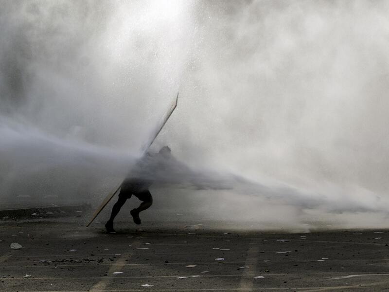 A demonstrator is hit by a riot police water cannon spray during a protest against the government in Santiago on November 18, 2019. President Sebastian Pinera condemned on Sunday for the first time what he called abuses committed by police in dealing with four weeks of violent unrest that have rocked Chile and which has left 22 people dead and more than 2,000 injured. Chileans have been protesting social and economic inequality, and against an entrenched political elite that comes from a small number of the