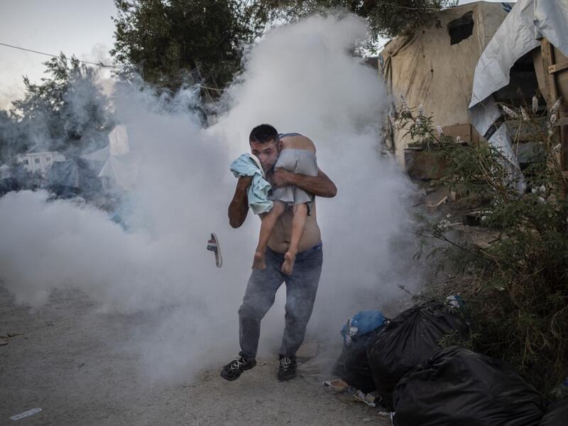A man holds a boy during clashes with police outside the refugee camp of Moria on the Greek island of Lesbos, on September 29, 2019. At least one migrant died on September 29, 2019, after a fire broke out in Moria, the over-crowded refugee camp on the Greek island of Lesbos, Greece's Health Ministry said. Police were firing tear gas to control crowds who started rioting after the fire ignited inside the camp, according to an AFP correspondent. ANGELOS TZORTZINIS / AFP